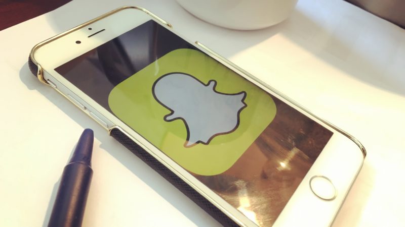 iPhone on Desk with Social SnapChat Icon on Screen