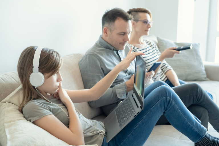 family-sitting-on-couch-consuming-media-on-different-devices