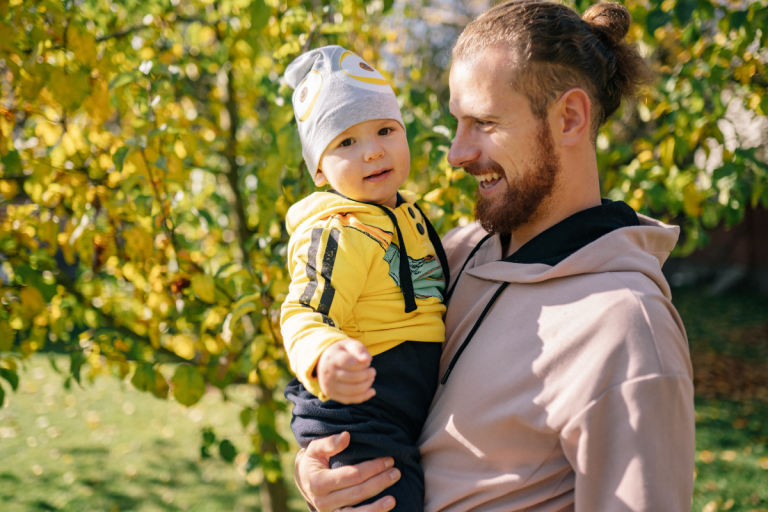 man-holding-child-outside-with-trees-in-background