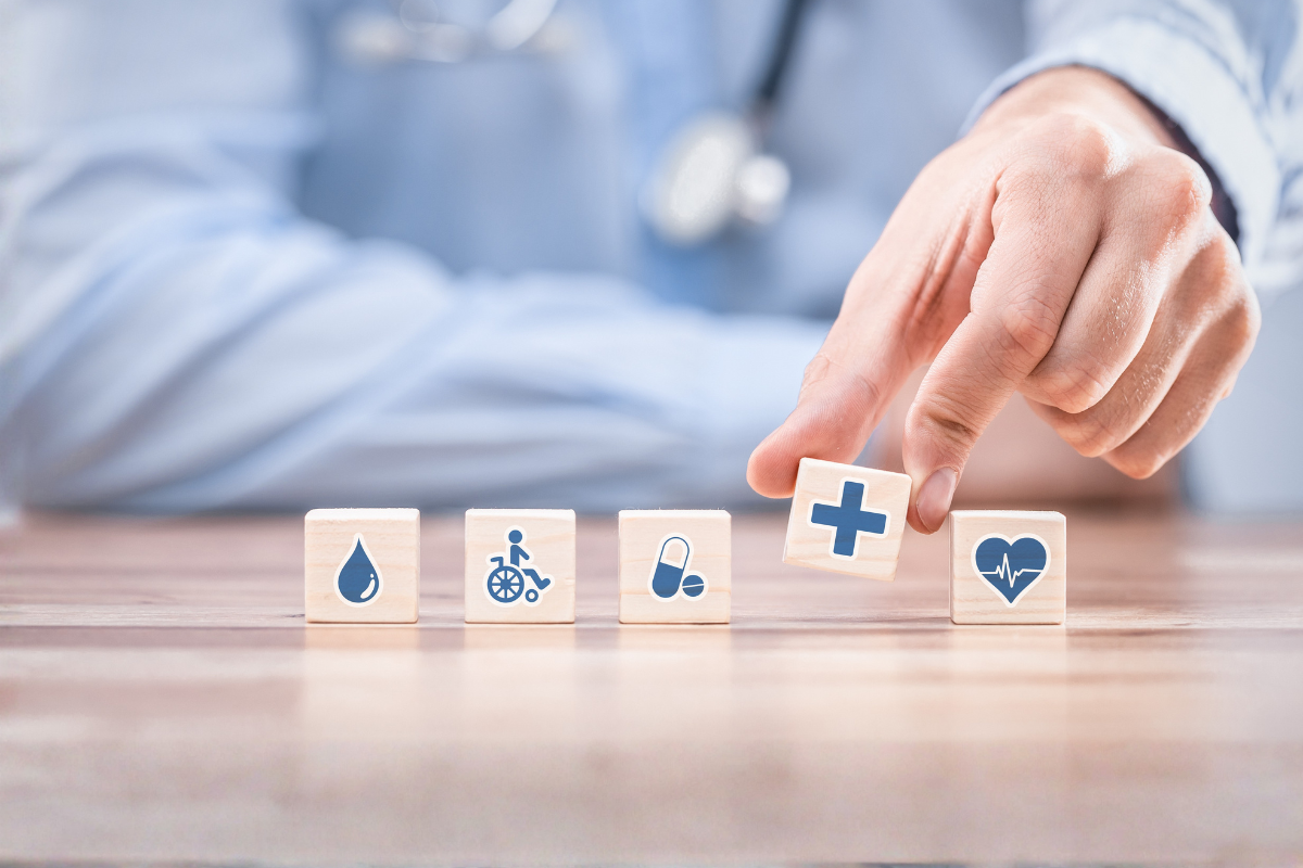 Medical professional lifting small blocks with different health relating icons pictured on them